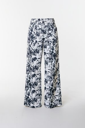 Bukser med vide ben i hvidt stof med sort pletemønster. Har en tætsiddende talje og forlommer for funktionalitet.