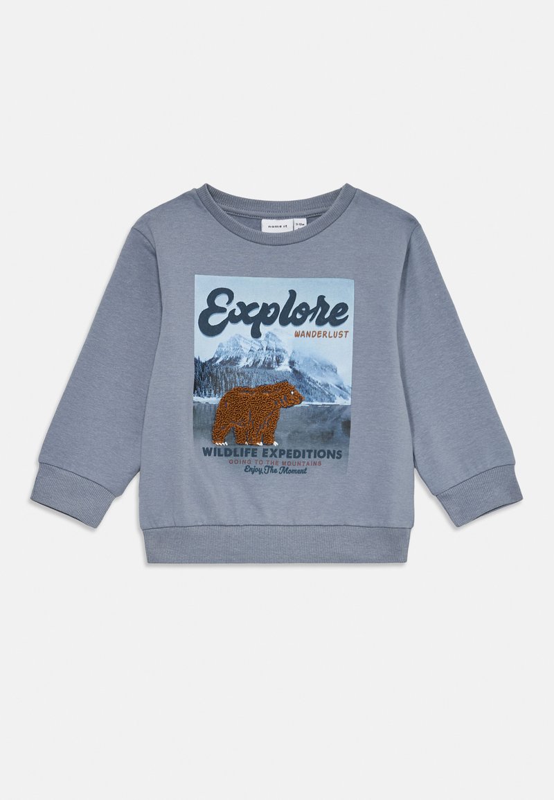 Kékes-szürke gyermek pulóver hegy és medve grafikával, rajta a "Fedezd fel", "Vándorló vágy" és "Vadállat Expedíciók" szövegekkel.