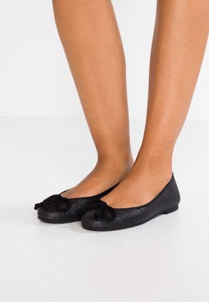 Ballerines noires avec une finition pailletée, bout rond, et nœuds texturés noirs à l'avant, semelle plate et intérieur lisse.
