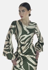Robe à manches longues verte et crème à motifs, avec une silhouette cintrée et un fini lisse, dotée d'un décolleté en V et de manches évasées.