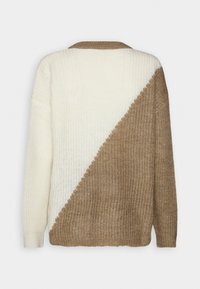 Neulepaita, jossa on geometrinen kuosi: yläosa on kermaisa ja alaosa ruskea. Teksturoitu kangas ja ribbireunus.