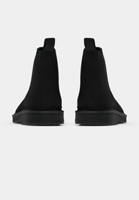 Černé kotníkové boty s hladkou texturou, elastickými bočními panely a plochou gumovou podrážkou. Minimalistický design bez viditelného značení nebo ozdob.