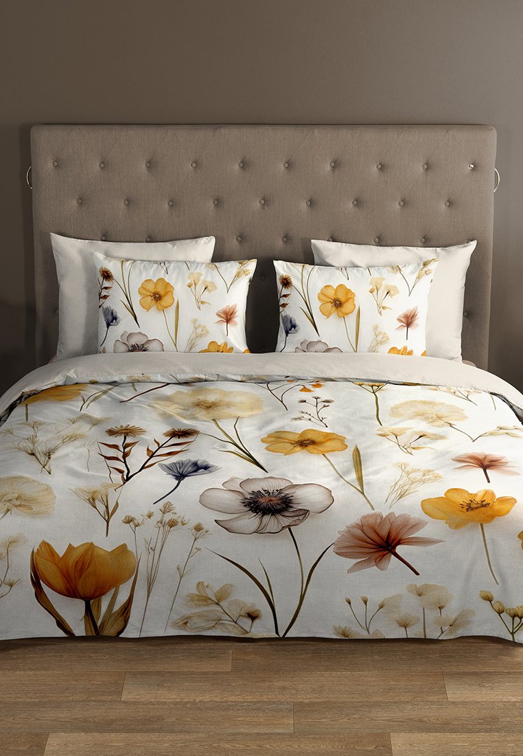 Blumenduvetüberzug aus weichem Stoff mit gelben, lila und weißen Blumen auf hellem Hintergrund, kombiniert mit passenden dekorativen Kissen.