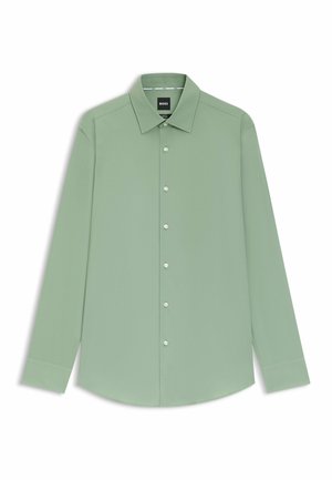 Camisa de vestir para hombre de manga larga color verde claro con cuello puntiagudo y botones blancos, colocada sobre un fondo blanco.