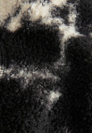 Zwart en crèmekleurige textuurstof met een zachte, krullende uitstraling, met verschillende patronen en een pluche oppervlak. Ideaal voor bovenkleding.