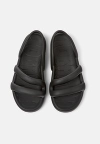 Black rubber sandals featuring a textured footbed, two wide straps across the top, and a smooth finish. Designed for comfort and ease of wear.