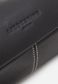 Svart läderplånbok med präglad "LIEBESKIND BERLIN"-logotyp och kontrasterande vit söm längs sömmen. Mjuk, texturerad yta.