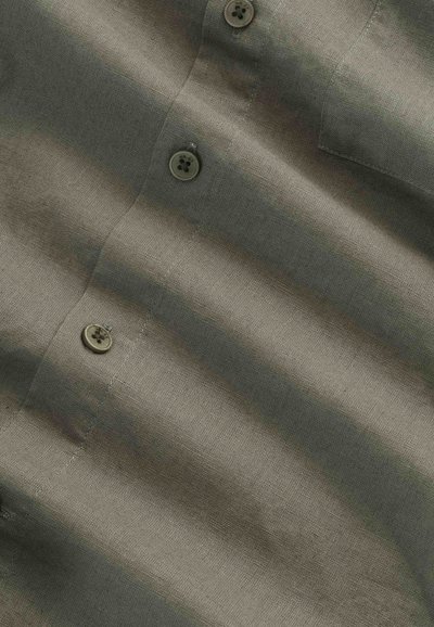 Brown cotton shirt fabric showing three buttons along the front placket with visible threads and stitching details.