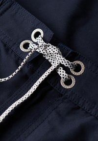 Shorts navy avec cordon de serrage à œillets métalliques, complétés par un cordon tressé blanc texturé et des détails de couture fins.