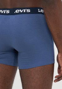 Kék pamut boxer alsónemű fekete derékkal, amelyen fehér "Levi's" logó található. Simaságot és passzos illeszkedést kínál.