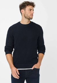 Donkerblauwe gebreide sweatshirt met een ronde halslijn, geribde mouwen en een losse pasvorm. De stof heeft een gestructureerde afwerking.