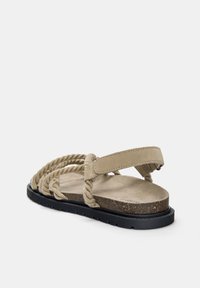 Sandal bej cu curele din sfoară împletită și un suport moale pentru picior. Talpă din cauciuc negru cu detalii texturate. Design deschis la spate pentru respirabilitate.