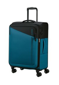 Valigia rigida blu con finitura testurizzata, dettagli neri, manico telescopico, quattro ruote e una tasca laterale.