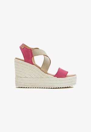 Sandalias de cuña con una suela de yute trenzado texturizado, tiras de ante rosa y un diseño de banda cruzada en tela beige.