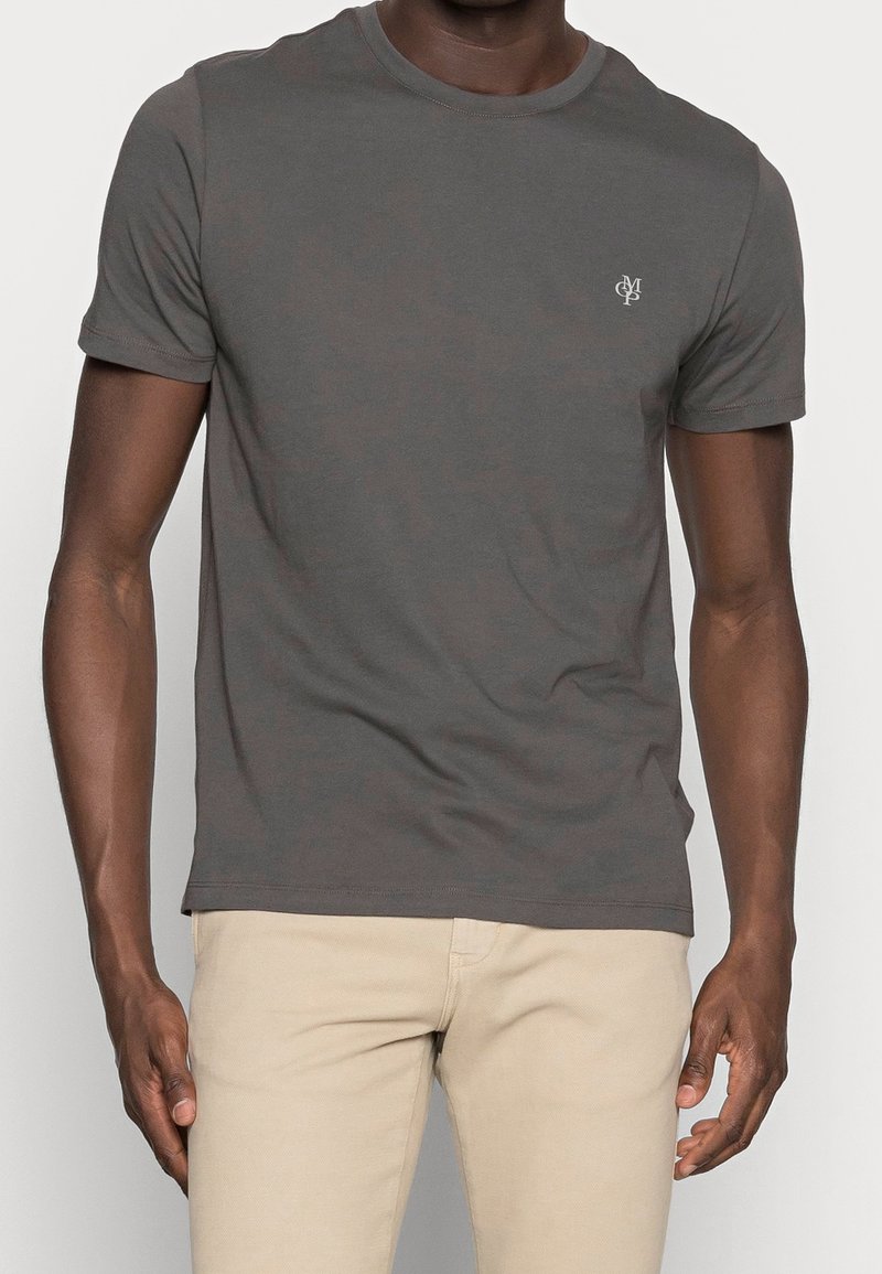 T-shirt en coton gris à manches courtes et col rond ; présente un petit logo sur la poitrine et une texture lisse et uniforme.