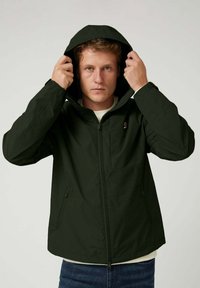 Chaqueta de color verde oscuro con cremallera y capucha, que cuenta con un bolsillo frontal y bolsillos laterales con cremallera, fabricada con un material suave y ligero.