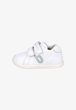 Zapatillas blancas para niños con dos correas de velcro, hechas de cuero. Presentan un logo gris y una suela texturizada para mayor agarre. Diseño de punta redondeada.