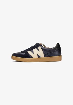 Marineblaue und cremefarbene Sneakers mit einem strukturierten Lederoberteil, das mit einem auffälligen "W"-Logo, Wildlederakzenten und einer hellbraunen Gummisohle versehen ist.