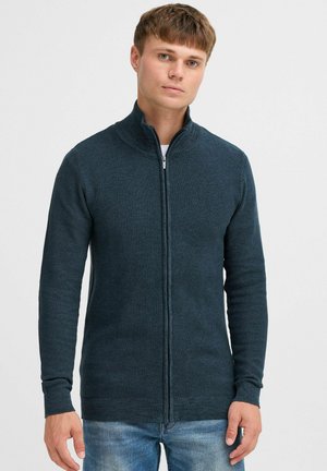 Mörkblå stickad zip-up tröja med hög krage, långa ärmar och ribbade muddar och nederkant. Texturerat tyg med en kroppsnära design.