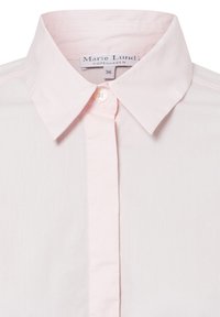 Jasny różowy, koszulowy T-shirt wykonany z gładkiej bawełnianej tkaniny. Posiada zapięcie na guziki oraz metkę z napisem "Marie Lund, Kopenhaga, 36."
