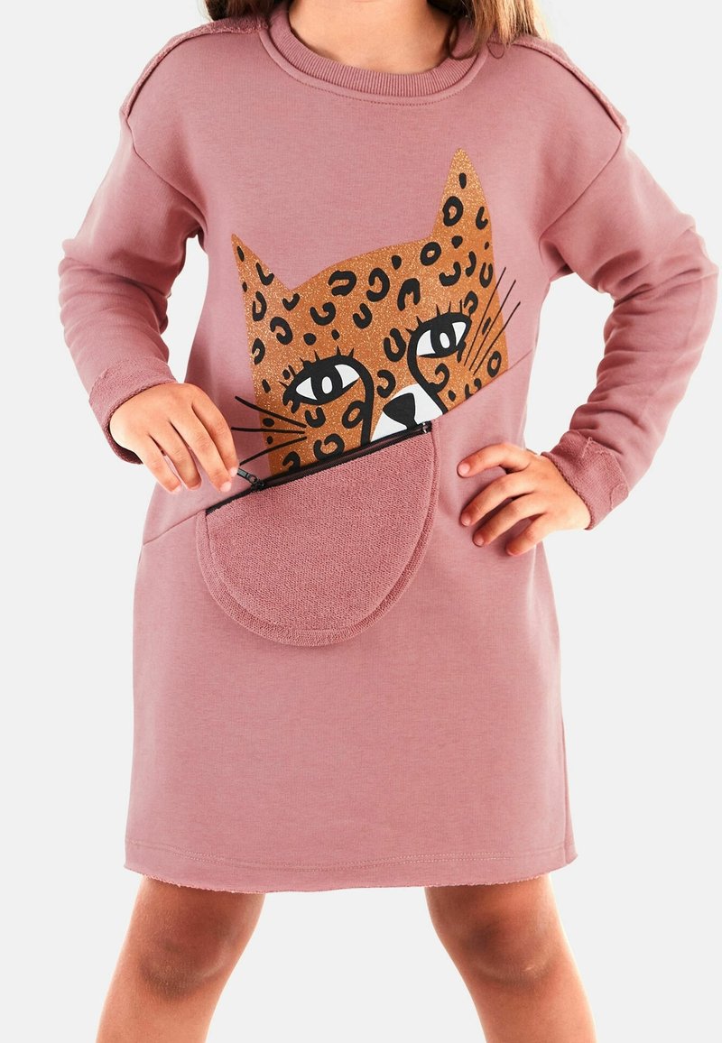 Enfant portant une robe rose avec un grand motif visage de léopard pailleté, levant la fermeture éclair sur une poche ovale à la taille.