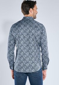 Dunkelblaues Hemd mit Blumenmuster, ausgestattet mit einem Button-Down-Kragen, langen Ärmeln und einem slim fit Design. Auffällige detaillierte Blumenmuster sind im gesamten Hemd zu sehen.