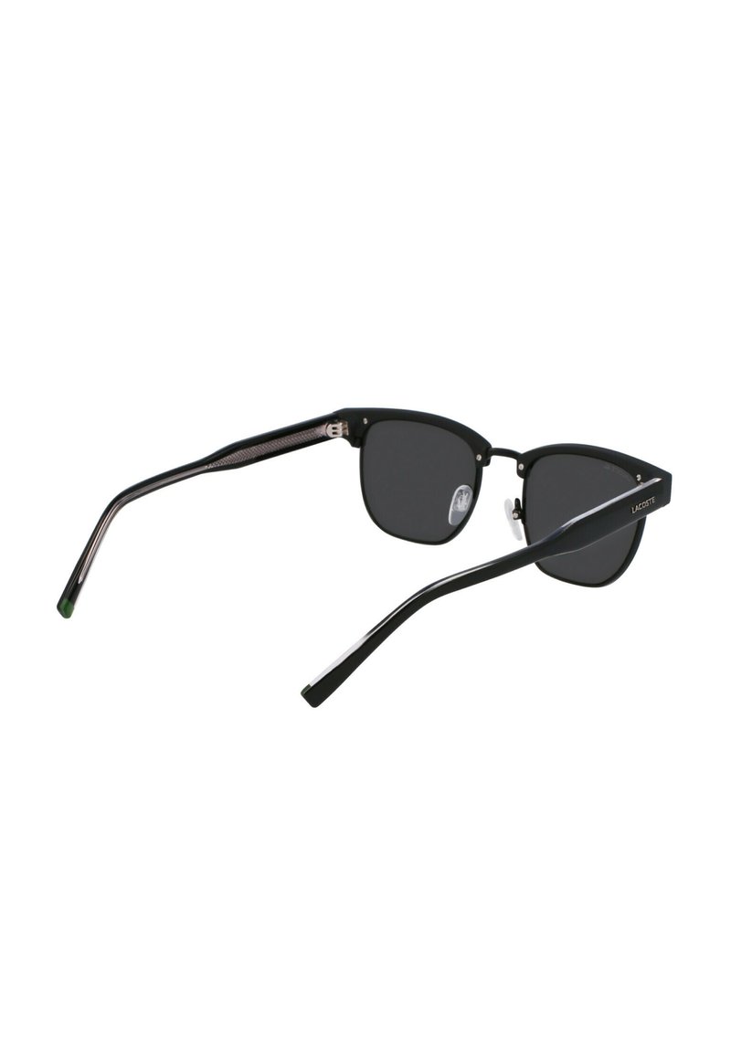 Schwarze, kantige Sonnenbrille mit dunklen Gläsern. Rahmen mit matter Oberfläche und silbernen Akzenten, die ein strukturiertes Muster am Bügel aufweisen.