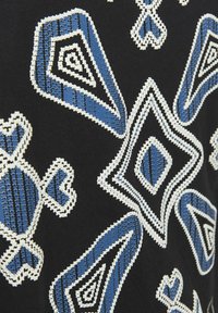 Tessuto nero con intricati motivi geometrici blu e bianchi, tra cui diamanti e forme stilizzate con dettagli testurizzati.