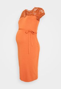 Gravidklänning i klart orange tyg, med spetsärmar och en figurnära passform, samt ett tygbälte knutet i midjan.