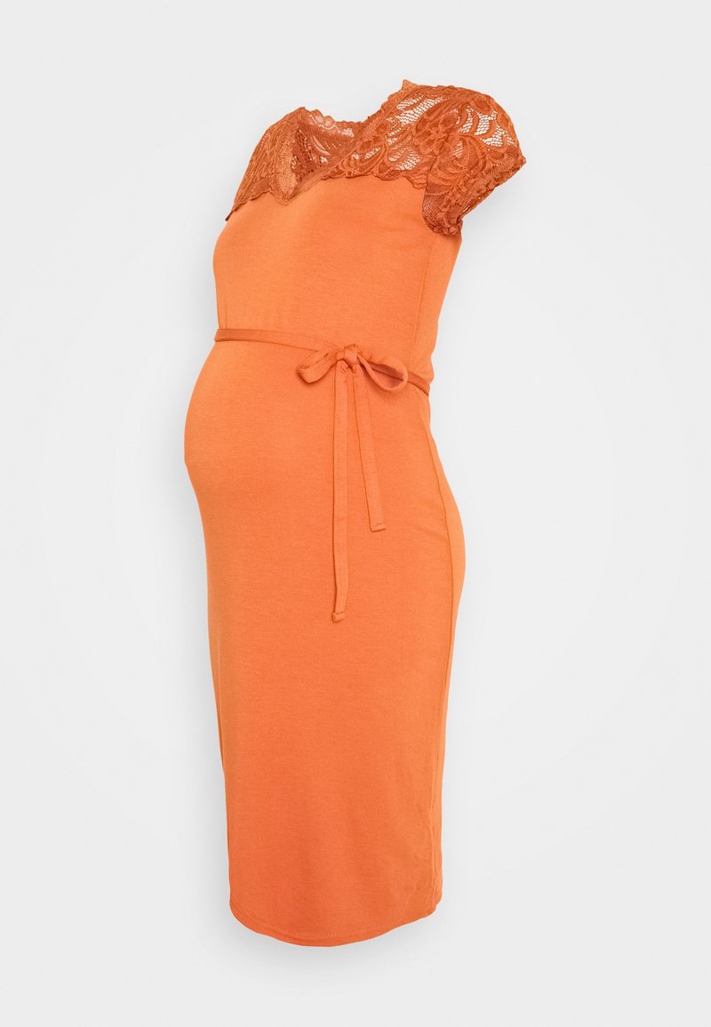 Gravidklänning i klart orange tyg, med spetsärmar och en figurnära passform, samt ett tygbälte knutet i midjan.