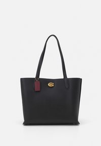 Black leather tote bag with two long handles, textured finish, gold hardware, and a burgundy tag. Spacious design with an open top.