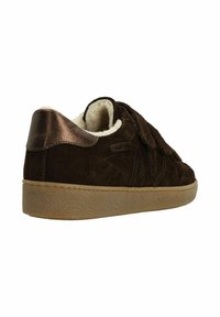 Brown suede sneaker with a textured rubber sole, featuring a soft cream lining, metal accents, and a velcro closure.