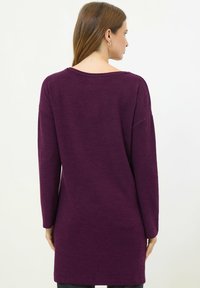 Abito maglione a maniche lunghe in tessuto viola scuro, con una vestibilità ampia, scollatura a barca e una texture morbida. Sottolinea delicatamente la forma del corpo.