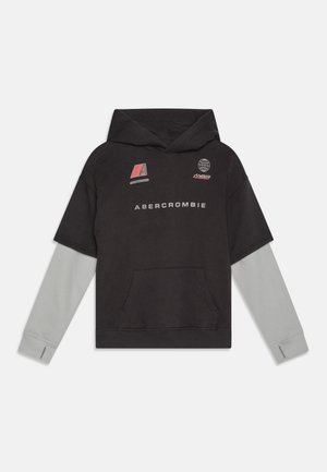 Felpa nera con maniche grigie, dotata di tasca frontale, testo "Abercrombie" e vari logo in rosso e bianco. Design morbido e casual.