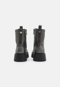 Sorte ankelstøvler i læder med en kraftig sål, lynlås på siden og trækstrop. Har en glat tekstur og rundet tådesign.