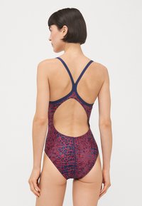 Costume da bagno intero con base blu navy e un motivo texturizzato rosso. Le spalline regolabili e il design con schiena scoperta migliorano la traspirabilità.