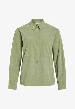 Šviesiai žalia kordurove marškiniai su mygtukais, ilgomis rankovėmis, dviem krūtinės kišenėmis ir klasikiniais atvartais.