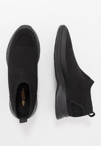 Scarpe slip-on nere realizzate in materiale a rete traspirante, con superficie testurizzata, suola in gomma e linguetta sul tallone per una facile calzata.