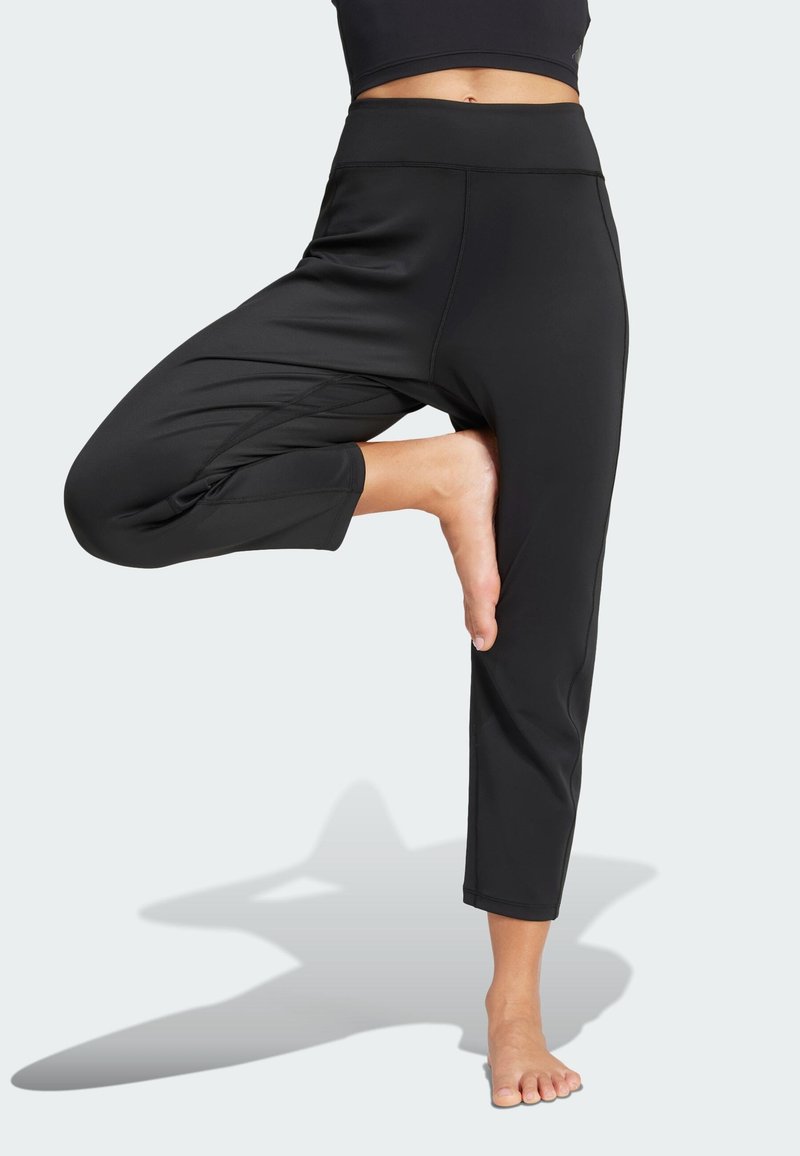 Čierne orezané nohavice z elastickej látky s vysokým pásom a voľným strihom. Hladká textúra bez viditeľných vzorov alebo kovových doplnkov.