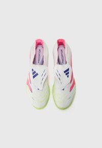 White soccer shoes with pink and green accents, featuring a sleek design, textured patterns on the surface, and a slip-on style.
