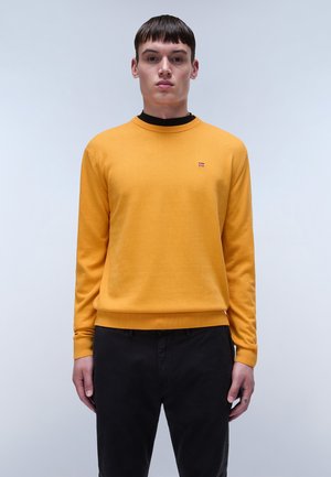 Geel gebreid trui met een ronde halslijn, geribbelde manchetten en boord. Klein logo op de borst. Gedirigeerd met zwarte broek.