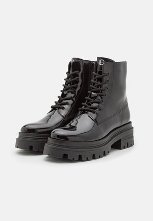 Botine negre din piele lăcuită, cu șirete în față, talpă groasă neagră și fermoar pe lateral. Prezintă o textură netedă și lucioasă, cu vârf rotund.