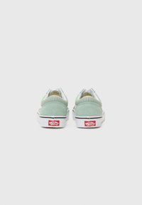 Zapatillas de ante verde con suelas de goma blanca, con un diseño de caña baja y acentos del logo de Vans en el talón. Textura suave.