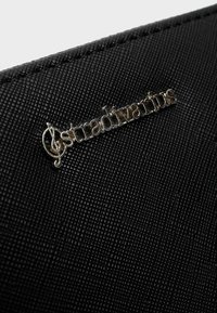 Portafoglio nero testurizzato con il logo "Stradivarius" in argento. Il materiale presenta un motivo in rilievo, che aumenta la presa e la durata.