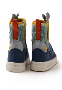 Botas de tobillo azules y grises con acentos texturizados en verde y amarillo, material suave y lengüeta de talón naranja. Suela de goma blanca, detalle de oreja redonda.