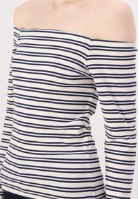 Ribikangast off-the-shoulder top, millel on tumesinised ja valged horisontaalsed triibud. Välja lõigatud mudel, millel on pikad varrukad ja tekstitud elastne materjal.