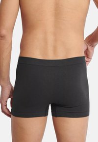 Sorte bomuldsboxershorts med en sømløs talje. Stoffet ser glat ud med et enkelt, tætsiddende design, der afslører den nederste del af ryggen.