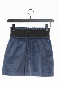 Námořnická modrá krátká sukně s černým elastickým pasem, se sklady a hladkou texturou, visící na černém ramínku.