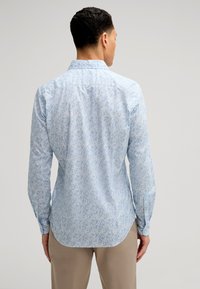 Camicia a maniche lunghe azzurro chiaro con motivo floreale, caratterizzata da un colletto strutturato e orli arrotondati, realizzata in un tessuto morbido e liscio.