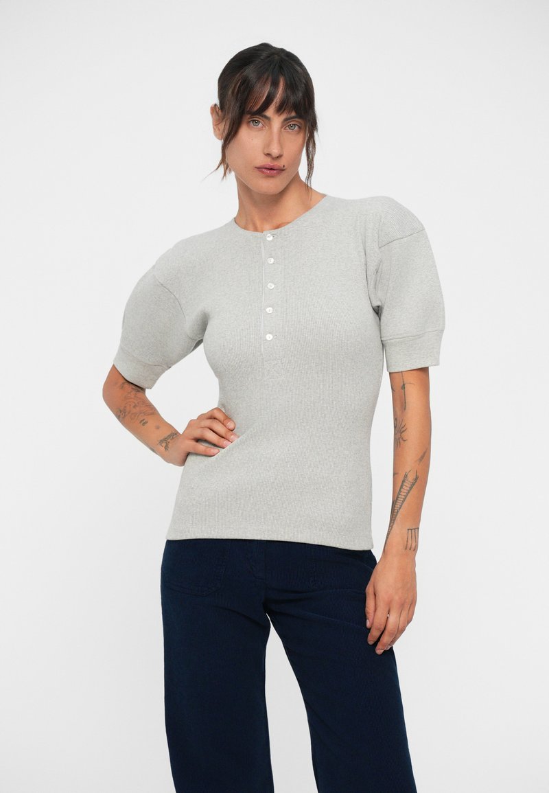 Light gray ribbed pullover top with short puff sleeves and a round neckline, featuring a placket of four buttons down the front.